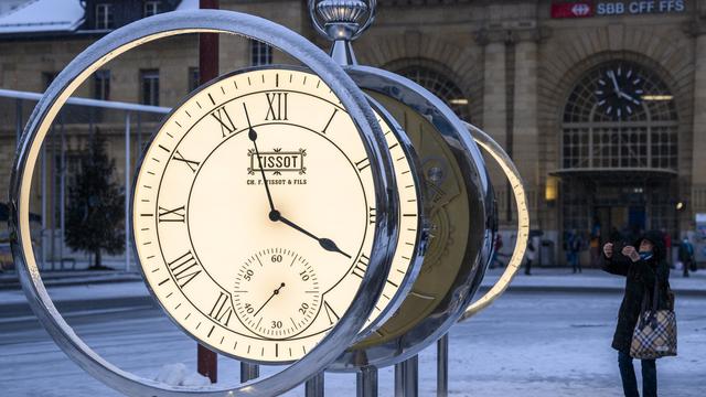 Une personne regarde la nouvelle horloge sur la place de la Gare à La Chaux-de-Fonds. [Keystone - Jean-Christophe Bott]