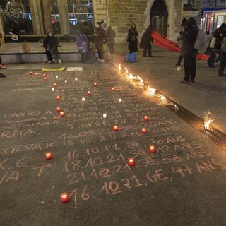 Des bougies et des noms de femmes victimes de féminicides écrits sur le sol lors d'un rassemblement suite à la 26e victime de féminicide en Suisse et contre les violences faites aux femmes, mardi 21 décembre 2021 à Genève. [KEYSTONE - Salvatore Di Nolfi]