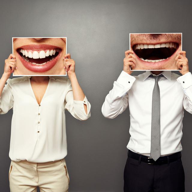 Deux personnes tiennent une photo de leurs bouches riantes devant leur tête. [Depositphotos - konstantynov]