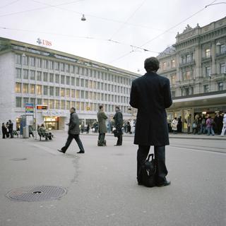 Un homme attend à l'arrêt de la place Paradeplatz à Zurich, en Suisse, devant les bâtiments de l'UBS et de la banque Credit Suisse pour le tram, photographié le 3 mars 2009. [KEYSTONE - Gaetan Bally]
