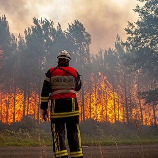 Samedi 16 juillet: un pompier face aux flammes à Landiras, en Gironde. [Keystone - SDIS 33 via AP]