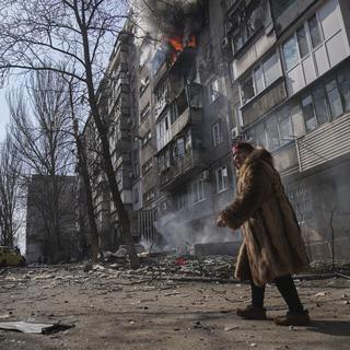 Une femme se déplace dans une rue de Marioupol, en Ukraine, après un bombardement russe le 13 mars 2022. [Keystone - AP Photo/Evgeniy Maloletk]