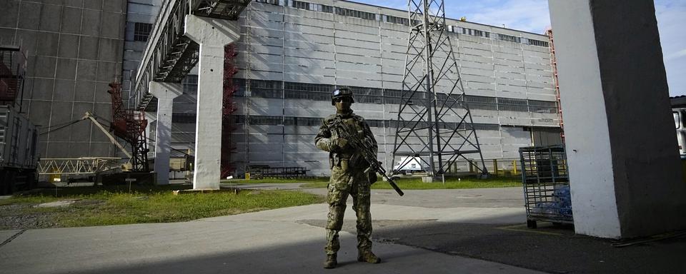 Un soldat russe devant la centrale nucléaire de Zaporijjia en Ukraine. [AP/Keystone]