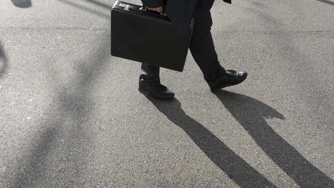 Un homme marche avec son attaché case à Zurich. [Keystone - Gaetan Bally]