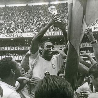 Le Brésilien Pelé soulevant le trophée Jules Rimet, après la victoire du Brésil à la coupe du monde au Mexique, le 21 juin 1970. [AP Photo/ Keystone - STF]