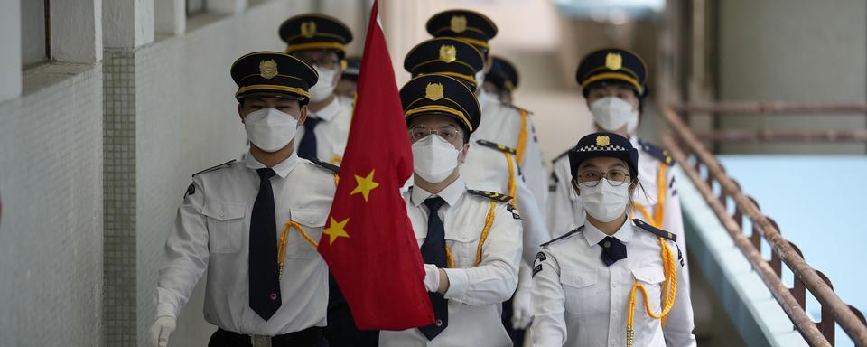 Des étudiants portant des masques faciaux assistent à une cérémonie de lever du drapeau national chinois dans une école secondaire pour marquer le 25e anniversaire de la rétrocession de Hong Kong à la Chine, à Hong Kong, jeudi 30 juin 2022. [AP Photo/KEYSTONE - Kin Cheung]