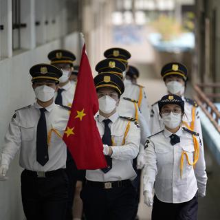 Des étudiants portant des masques faciaux assistent à une cérémonie de lever du drapeau national chinois dans une école secondaire pour marquer le 25e anniversaire de la rétrocession de Hong Kong à la Chine, à Hong Kong, jeudi 30 juin 2022. [AP Photo/KEYSTONE - Kin Cheung]