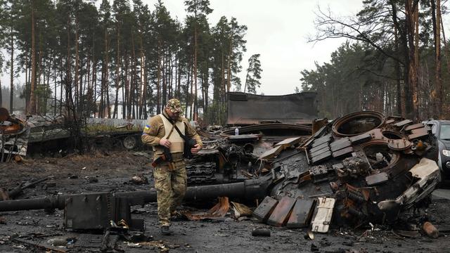 Soldat ukrainien devant un char russe détruit à Dmytrivka, près de Kiev, 02.04.2022. [AP/Keystone - Efrem Lukatsky]