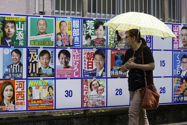 A Tokyo, une femme passe devant les affiches des candidats au Sénat. [Keystone - Kimimasa Mayama]