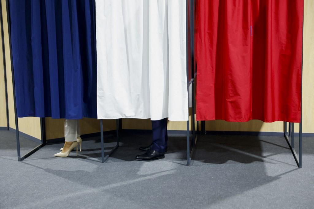 Brigitte Macron et Emmanuel Macron dans l'isoloir dimanche au Touquet (Pas-de-Calais) pour le deuxième tour de l'élection présidentielle française. [AFP - Gonzalo Fuentes]