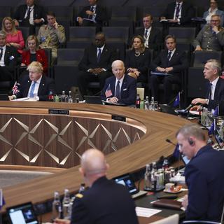 Le premier ministre britannique Boris Johnson, assis à gauche, et le président Joe Biden, écoutent le secrétaire général de l'OTAN Jens Stoltenberg s'exprimer lors d'une réunion du Conseil de l'Atlantique Nord pendant un sommet de l'OTAN consacré à l'invasion de l'Ukraine par la Russie, au siège de l'alliance, le jeudi 24 mars 2022 à Bruxelles. [Pool via AP/KEYSTONE - Evelyn Hockstein]