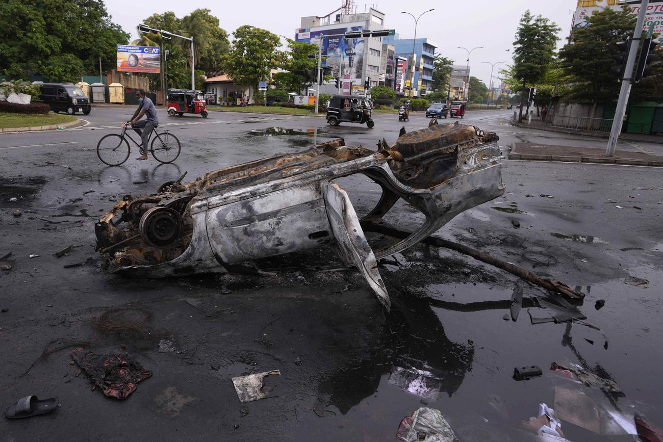 Mardi 10 mai: une voiture brûlée à un carrefour de Colombo, au Sri Lanka, au lendemain des affrontements entre partisans du gouvernement et manifestants anti-gouvernementaux qui ont entraîné la démission du Premier ministre. [Keystone - AP Photo/Eranga Jayawardena]
