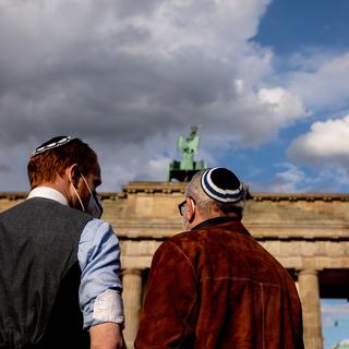 Des allemands juifs portant la kippa protestent contre l'antisémitisme dans le monde devant la porte de Brandenburg, à Berlin. [Keystone/EPA - Filip Singer]