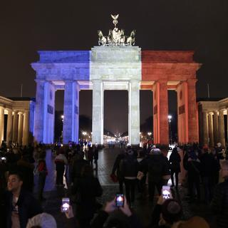 À Berlin, la porte de Brandenburg est illuminée avec le drapeau tricolore de la France. [Keystone/EPA - Kay Nietfeld]