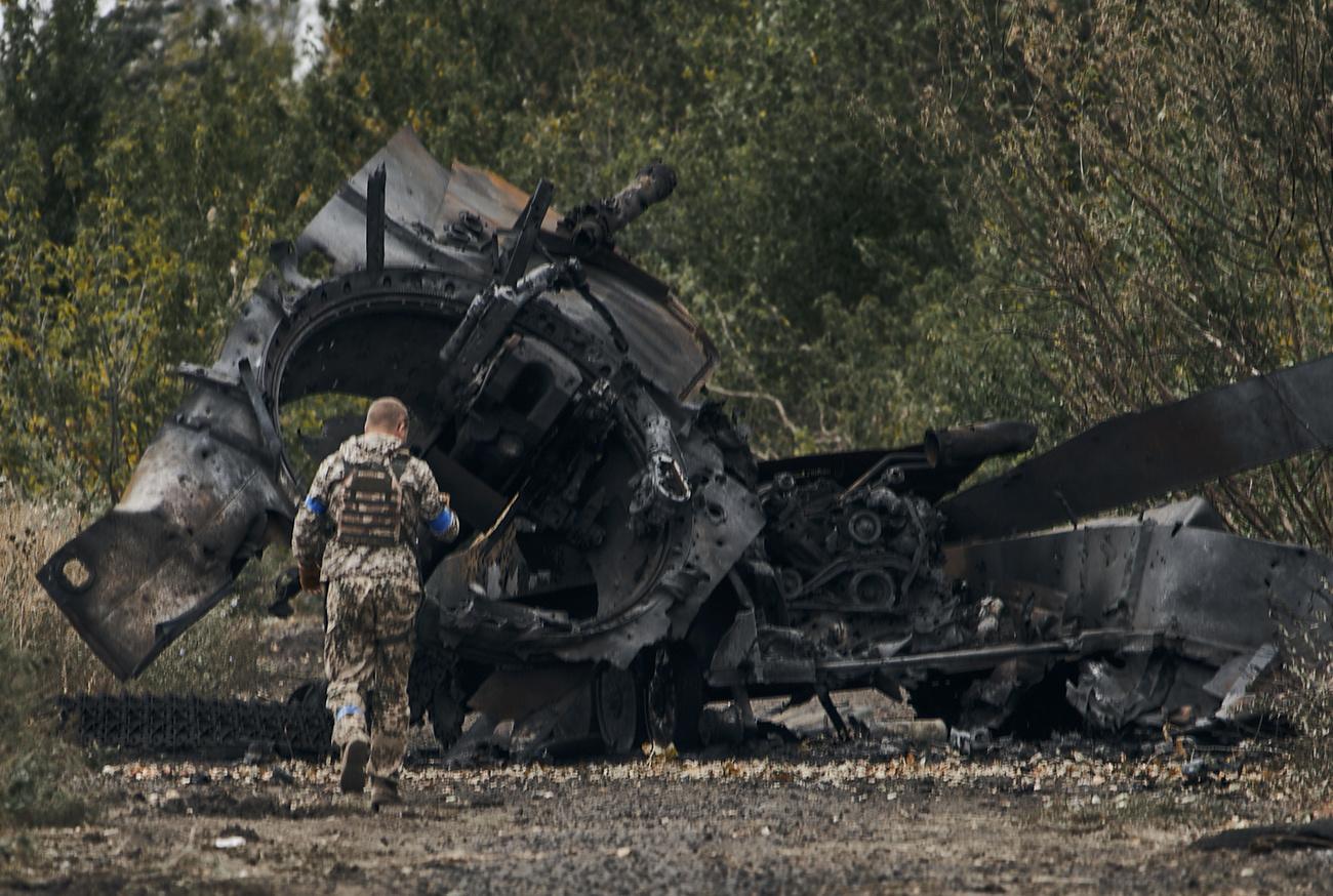Un soldat ukrainien passe à côté d'un char d'assaut russe détruit, dans la région de Kharkiv, le 11 septembre 2022. [AP/Keystone]