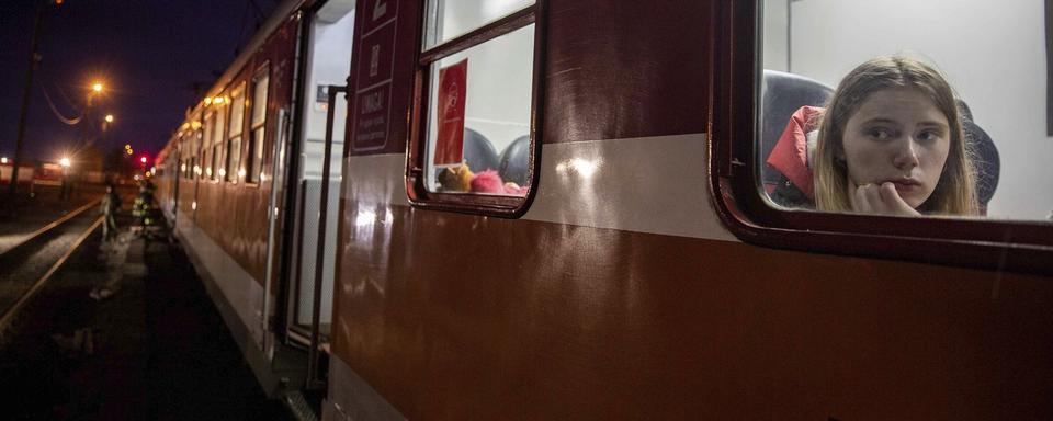 Une femme dans un train en Pologne après avoir fuit l'Ukraine. [AP Photo/Keystone - Visar Kryeziu]