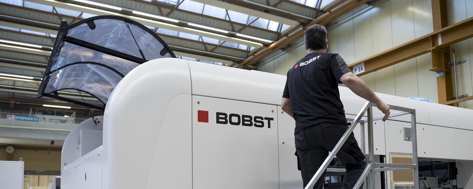 Un employé de l'entreprise Bobst devant une machine de découpe de carton. [Keystone - Jean-Christophe Bott]