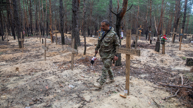 Un soldat ukrainien dans un cimetière improvisé à Izioum. [Reuters - Oleksandr Khomenko]