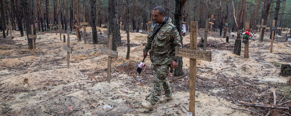 Un soldat ukrainien dans un cimetière improvisé à Izioum. [Reuters - Oleksandr Khomenko]