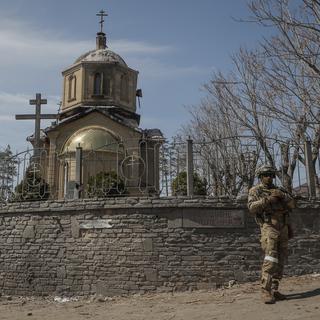 Un militaire russe monte la garde près d'une église dans le centre-ville de Volnovakha, en Ukraine, le 11 avril 2022. [EPA/KEYSTONE - Sergei Ilnitsky]