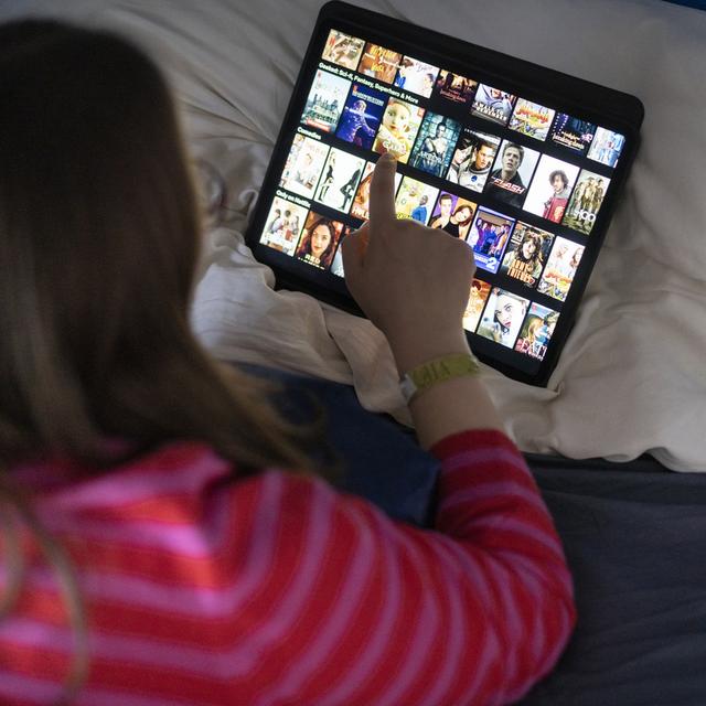 Une femme utilise la plateforme de streaming Netflix sur sa tablette. [Keystone - Gaëtan Bally]