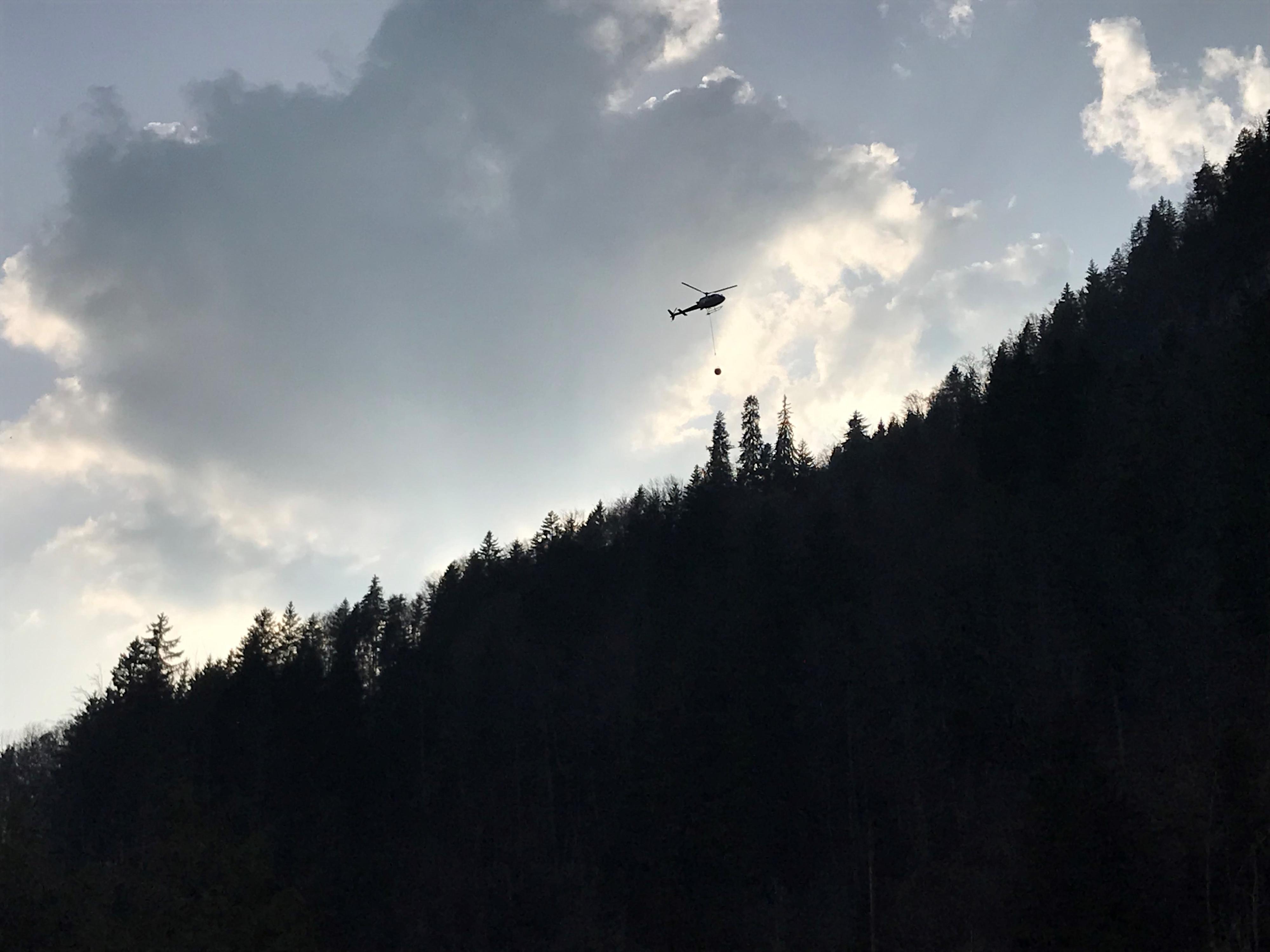 Un hélicoptère tente d'éteindre un feu de forêt dans la région de Leysin. [RTS - Maude Richon]