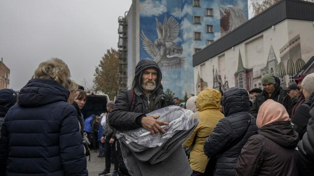 Un homme qui vient de récupérer une couverture à Kherson. [afp - Bulent Kilic]