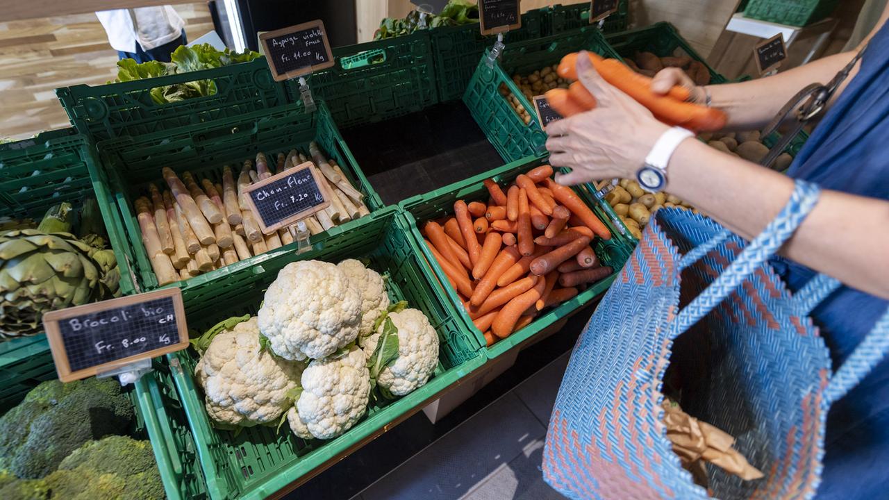 Une personne achète des légumes à la ferme du Lignon, à Genève, à l'occasion de la Journée portes ouvertes à la ferme, dimanche 2 juin 2019. [KEYSTONE - Martial Trezzini]