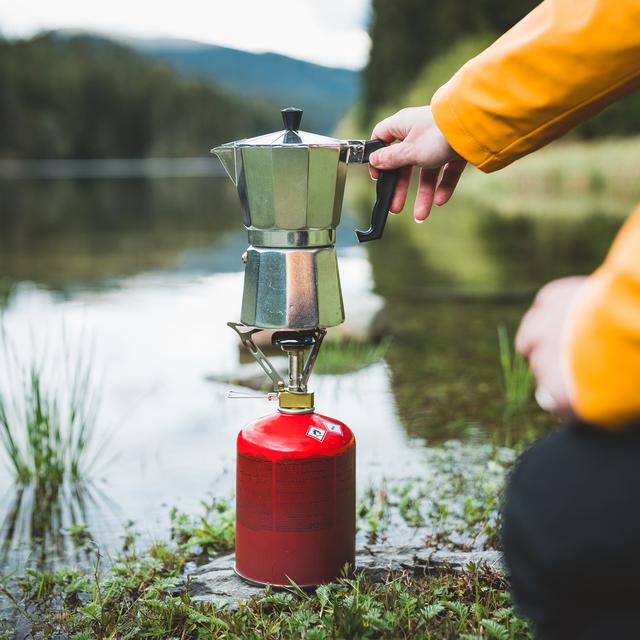 Un réchaud de camping et une cafetière au bord d'un lac. [Depositphotos - Claudiumaxim]