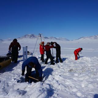 Une équipe de recherche creuse pour récolter des sédiments au lac Hazen en mai 2017. Leur étude sur un possible "débordement viral" de l'Arctique dû au réchauffement climatique a été publiée le 19 octobre 2022. [AFP - Graham Colby]