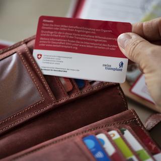 Une femme sort de son porte-monnaie sa carte de don d'organes de Swisstransplant, la Fondation nationale suisse pour le don et la transplantation d'organes, photographiée le 30 avril 2021 à Uster. [KEYSTONE - Christian Beutler]