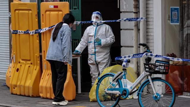 Un garde devant un bâtiment confiné à Shanghai. [Keystone/EPA - Alex Plaveski]