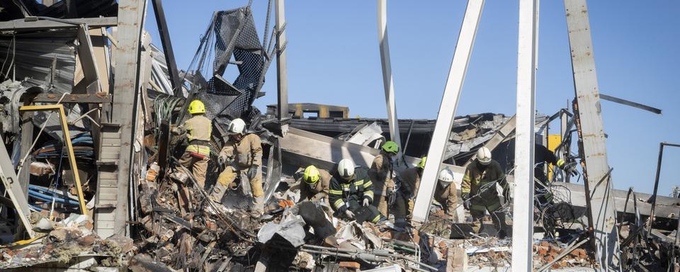 Les pompiers des services d'urgence de l'État ukrainien travaillent pour enlever les débris dans un centre commercial incendié après une attaque à la roquette à Krementchouk, en Ukraine, le mardi 28 juin 2022. [AP Photo/ Keystone - Efrem Lukatsky]