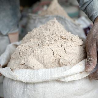Un ouvrier yéménite scelle un sac de farine de blé importée dans une minoterie à Sana'a, au Yémen, le 23 mars 2022. [EPA/KEYSTONE - Yahya Arhab]