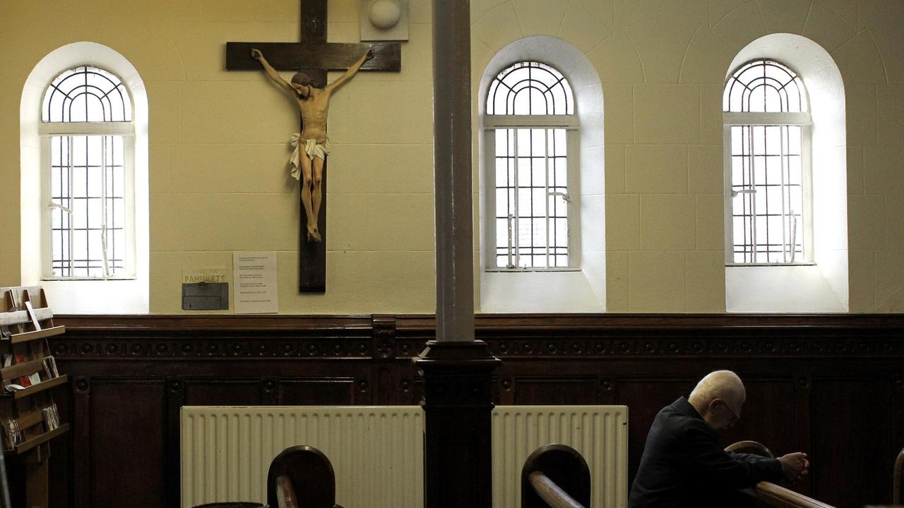 Un homme prie pendant la messe à l'église catholique romaine St Mary à Belfast, en Irlande du Nord. [KEYSTONE - Peter Morrison / AP Photo]