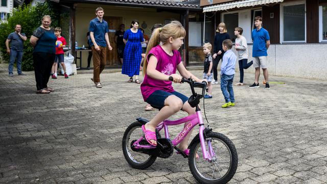 Des enfants et des adultes ukrainiens de la région de Marioupol jouent dans la cour de la maison de l'association tipiti à Gilly, dans le canton de Vaud. [KEYSTONE - Jean-Christophe Bott]