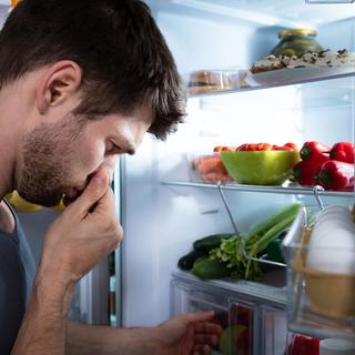 Un homme se bouche le nez en sentant l'odeur de l'intérieur de son frigo. [Depositphotos - AndreyPopov]