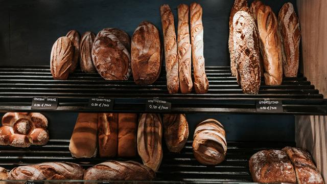 Une étagère remplie de pains dans une boulangerie. [Unsplash - Angelo Pantazis]