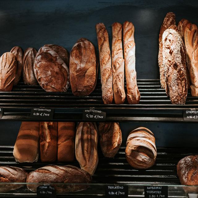 Une étagère remplie de pains dans une boulangerie. [Unsplash - Angelo Pantazis]