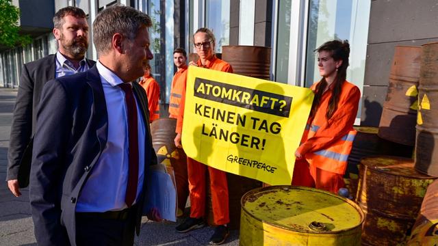 Des activistes de Greenpeace accueillent le ministre allemand Robert Habeck avant une conférence de presse sur le nucléaire le 5 septembre 2022. [AFP - John MacDougall]