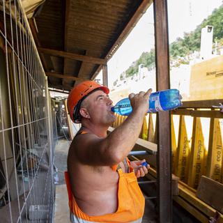 Un ouvrier sur un chantier s'hydrate pendant un épisode de canicule. [Keystone - Francesca Agosta]