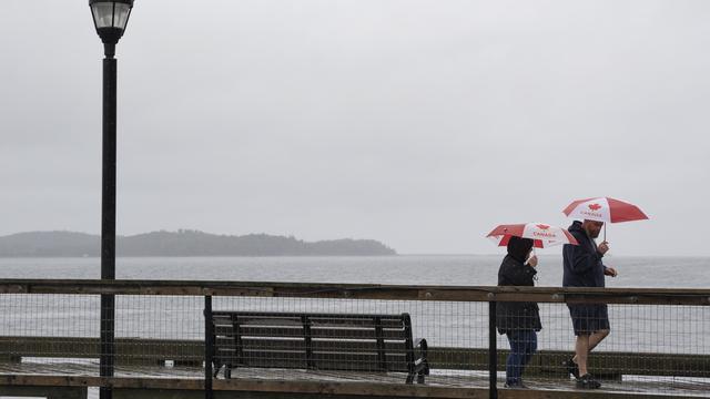 Des piétons se protègent avec des parapluies en marchant le long du front de mer d'Halifax, avant que l'ouragan Fiona ne touche terre [Keystone]