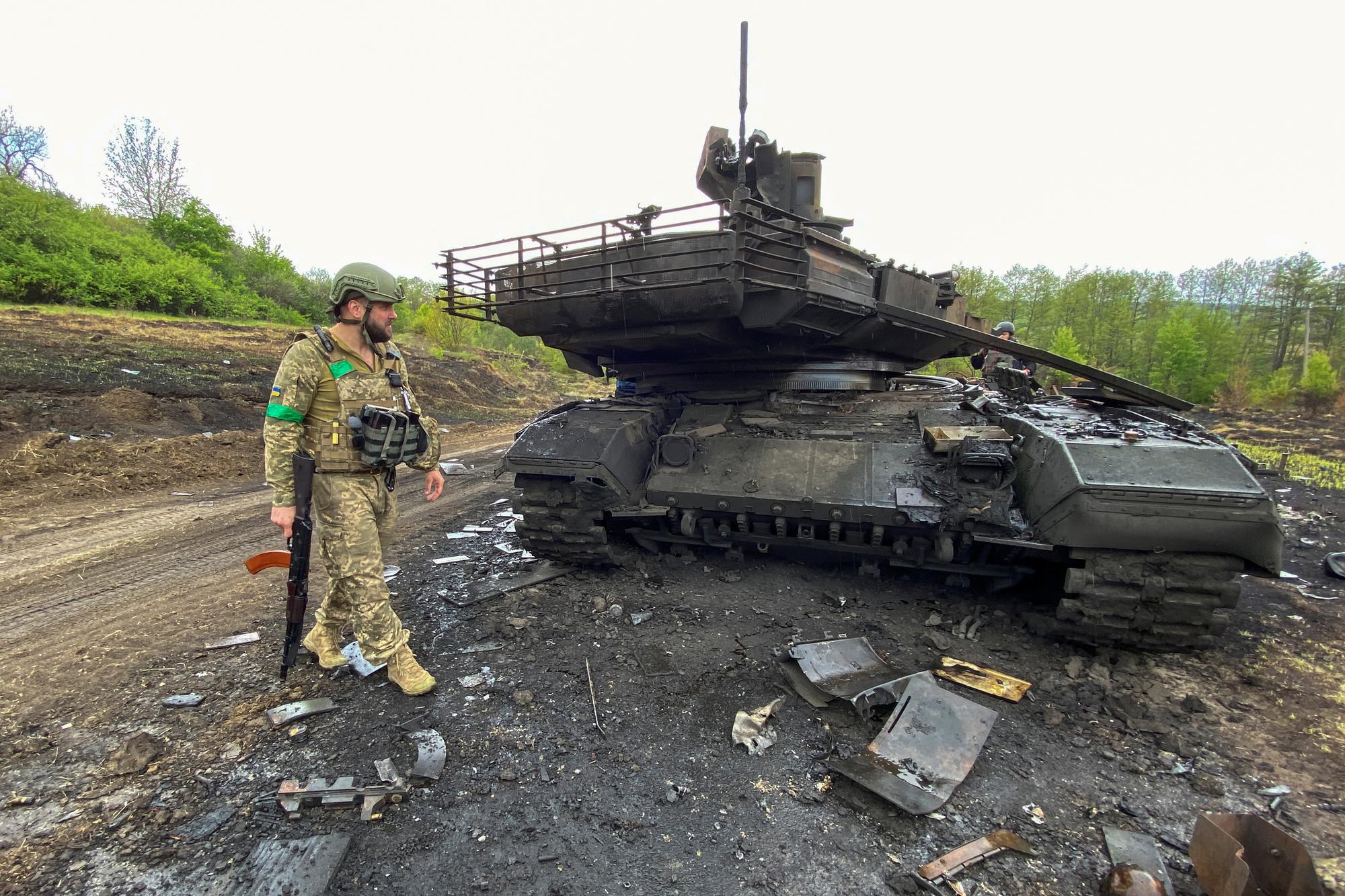 Un soldat ukrainien devant un char russe détruit dans la région de Kharkiv. [Reuters - Vitalii Hnidyi]