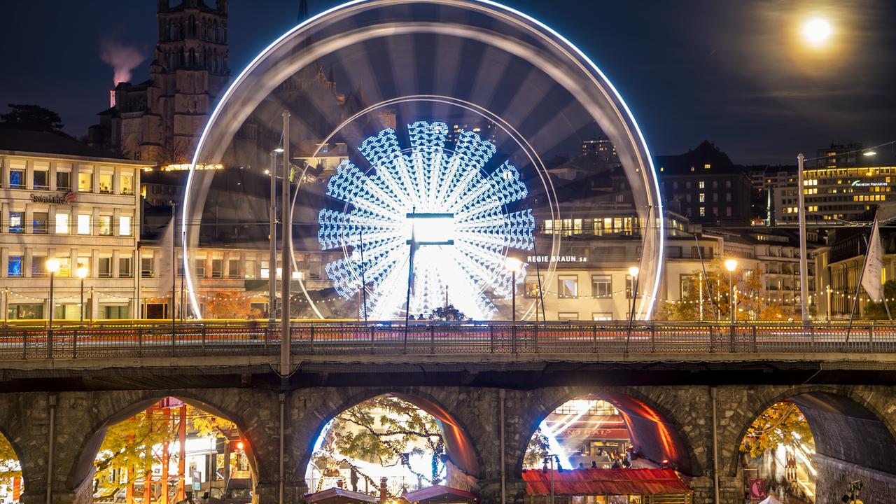 La grande roue installée sur la place Centrale tourne lors de l'ouverture du "Bô Noël", le jeudi 18 novembre 2021 à Lausanne. [Keystone - Jean-Christophe Bott]