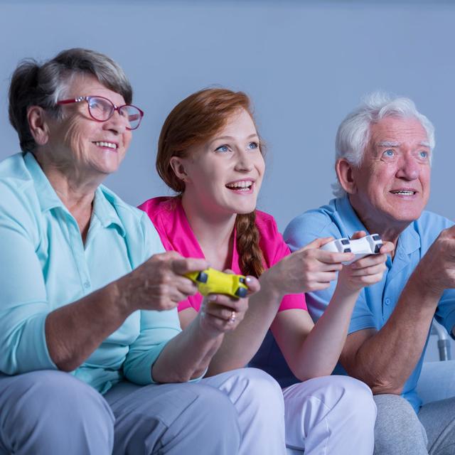Une jeune fille joue aux jeux vidéos avec ses grand-parents. [Depositphotos - photographee.eu]