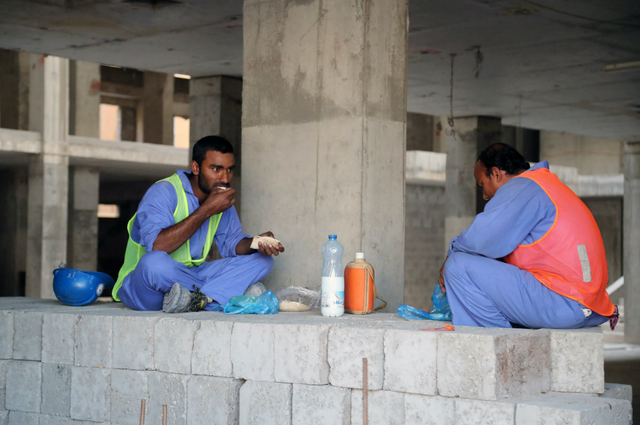 Des travailleurs migrants mangent sur leur site de construction à Doha au Qatar [STRINGER / AFP]