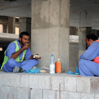 Des travailleurs migrants mangent sur leur site de construction à Doha au Qatar [STRINGER / AFP]