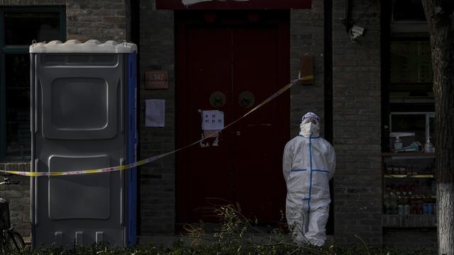 Un travailleur chargé de surveiller un quartier confiné à Pékin. [AP Photo/Keystone - Andy Wong]