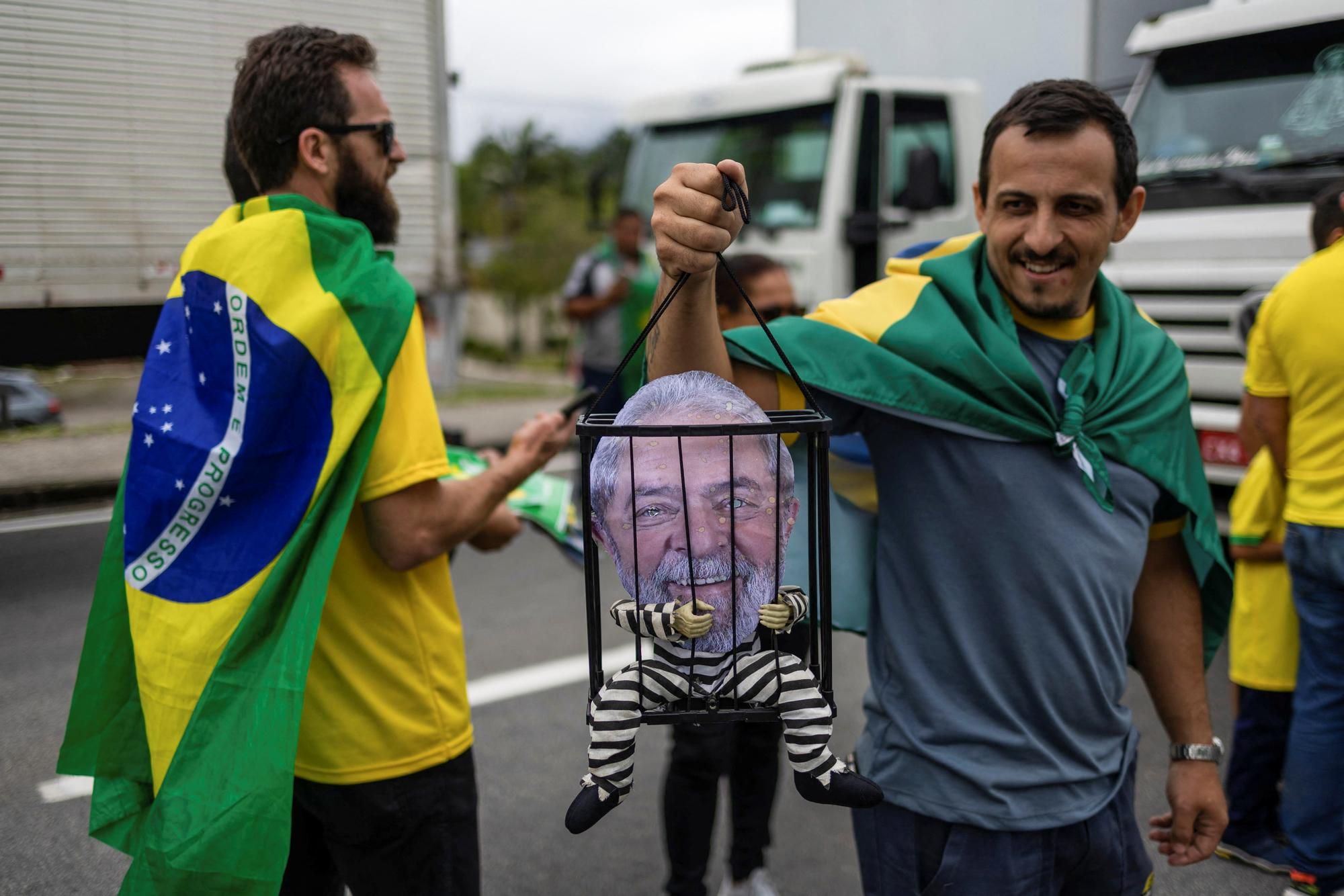 Des supporters de Jair Bolsonaro bloquent une route dans l'Etat de Sao Paulo. L'un d'eux tient une marionnette représentant le président élu Lula dans une cage. [REUTERS - Roosevelt Cassio]