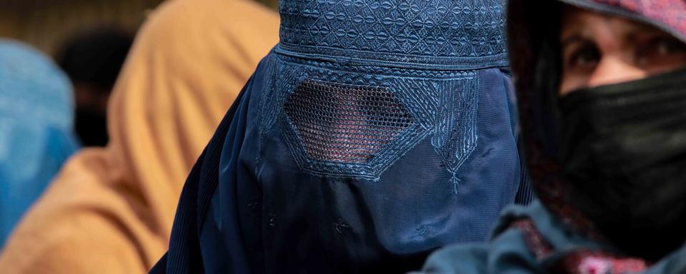 Une femme afghane vêtue d'une burqa marche sur une route à Kaboul, en Afghanistan, le 27 décembre 2021. [EPA/KEYSTONE - Stringer]